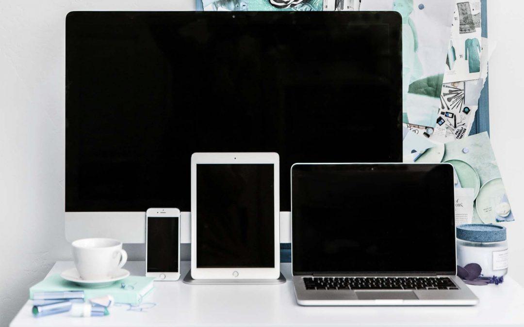 Computer, laptop, tablet, phone and coffee mug on a desk